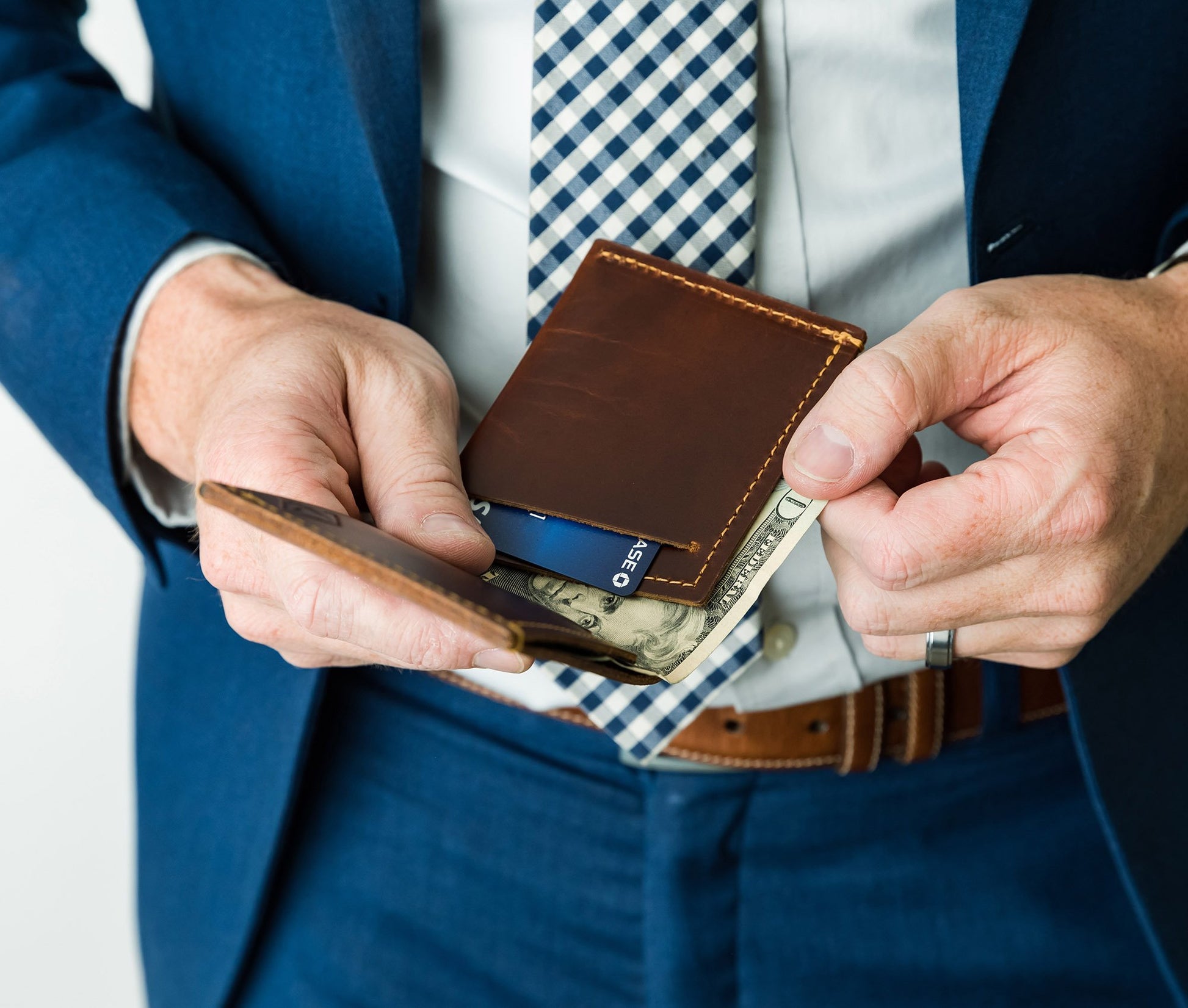 Person in a suit opening a brown leather wallet with money and a card. personalized gift for dad 