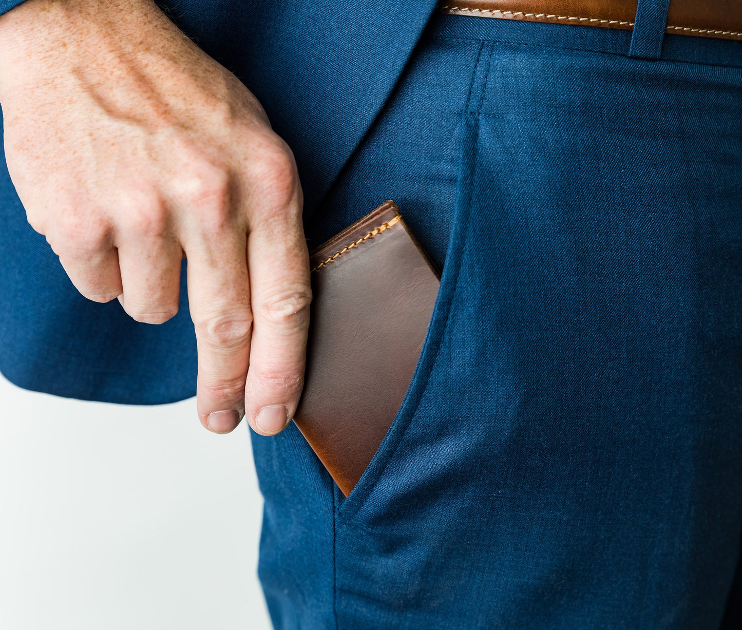 Person wearing a blue suit with a brown leather wallet in the pocket on a white background personalized gift for dad